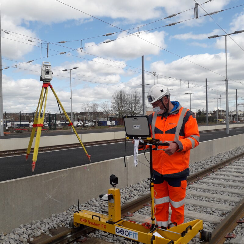 Géomètre debout utilisant un chariot ferroviaire GRP3000 pour effectuer des mesures sur les rails de train.